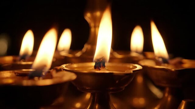 Many lit diyas oil lamps with bright yellow flames glowing in the dark, spiritual, festive, warm atmosphere