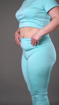 Overweight woman pulling up shapewear leggings to fat belly, flabby tummy after pregnancy, weight loss concept, vertical video