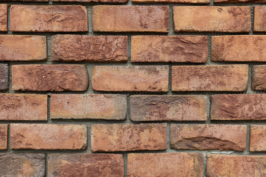 Textured rustic orange and brown brick wall surface close-up