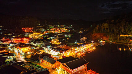 Fototapeta premium At dusk the reflections of the lights from the village the lake in Chinese-style structures with colorful lights lined the waterfront. Ban Rak Thai is a popular tourist attraction in Mae Hong Son