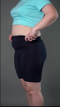 Fat woman pulling up corrective shapewear, flabby belly after pregnancy, overweight female body, vertical video