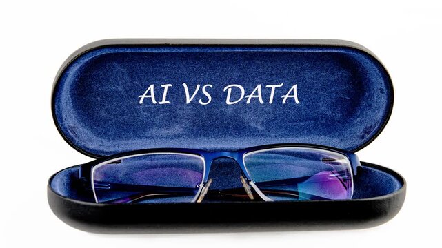Close up of blue framed glasses sitting inside a matching blue velvet lined case. The words AI VS DATA are clearly visible on the case lid