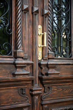 Brass door handle on carved wooden entrance, restored historic door detail, Odesa Ukraine