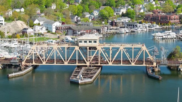 Mystic River harbor and town aerial video, a scenic drone shot tracking over boat marinas, waterfront docks, historic bridges, and historic coastal neighborhoods on a sunny day in Connecticut.
