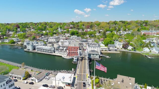 Mystic River Bascule Bridge aerial view, a high-angle drone video showing cars crossing the iconic drawbridge near downtown storefronts and the waterfront on a bright spring day in Mystic Connecticut.