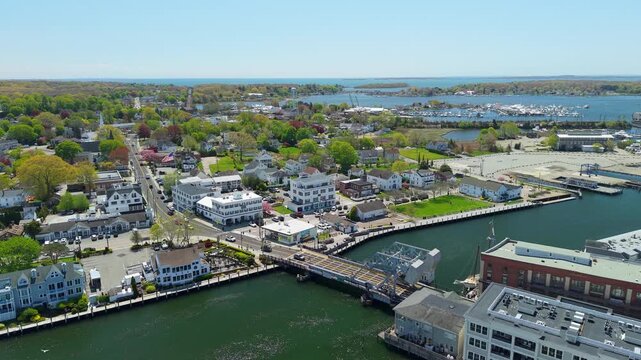 Mystic River Bascule Bridge aerial view, a high-angle drone video showing cars crossing the iconic drawbridge near downtown storefronts and the waterfront on a bright spring day in Mystic Connecticut.
