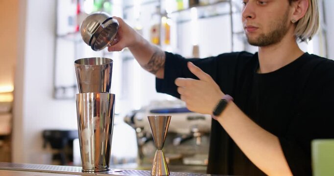 Cocktail making. Mixologist work. Bartender hand squeezing juice to metal shaker. Preparing aroma flavored beverage at pub counter.