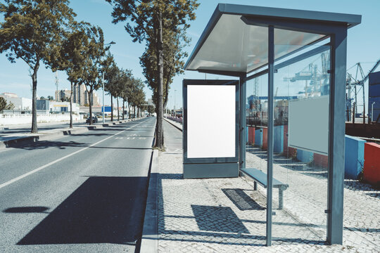 Modern glass bus stop with large blank poster frame on quiet city street, realistic outdoor advertising display mockup for campaign, branding and media design