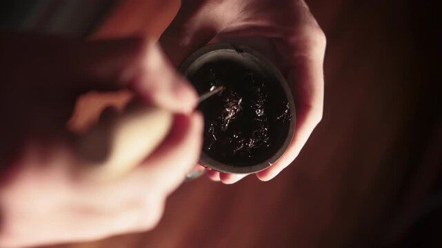 Traditional hookah. Ritual preparing. Man hands blending fruit tobacco using metallic tool making mix in cafe workplace.