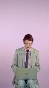 Young androgynous person working on a laptop computer