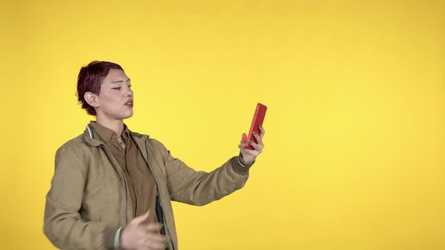 Young woman with short hair taking selfies on a yellow background