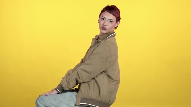 Young woman with pixie cut posing on yellow background