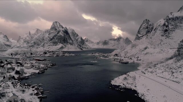 Serene winter village nestled by a dark fjord surrounded by snow-capped mountains