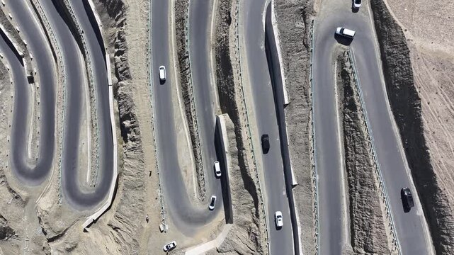 Cars on winding hairpin mountain road in dry desert landscape
