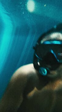Vertical Underwater Video of Man Free Diving in Cenote Near Puerto Morelos With Sun Beams Through Water