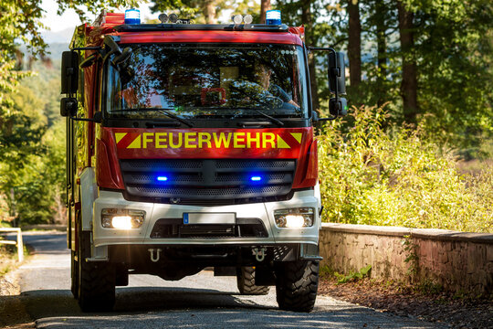 German LF 10 fire truck driving on road with blue emergency lights