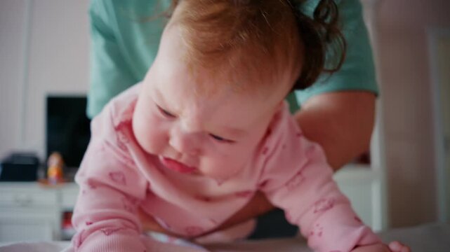Close up of a baby being gently supported during tummy time on a padded table