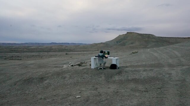Man Editing Video at Computer Desk in Desert Workspace