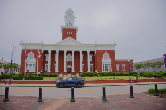 Historic Red Brick Lee County Courthouse With Clock Tower and Classical Columns in Small Town Civic Square Editorial Use Only, Opelika, AL  USA, May 12, 2026. American flags and manicured landscaping 