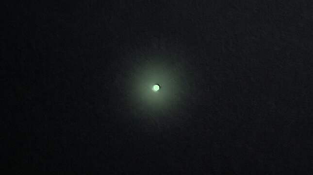 A glowing green orb shines brightly in the dark night sky