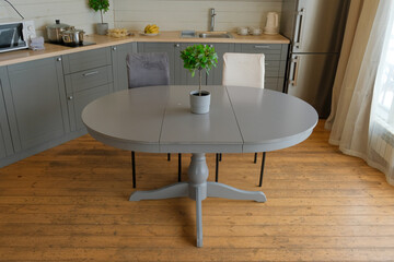 Fototapeta premium Dining room interior. Gray oval dining table, wood flooring, grey cabinets. Interior design of stylish kitchen with family table, modern chairs. Wooden floor. White wall. Template. New Luxury Home.