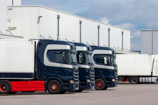 Modern blue cargo truck delivery van parked logistics warehouse center complex building exterior bay. Semi-trailer lorry unload goods distribution blue sky. Cargo storage facility industry building