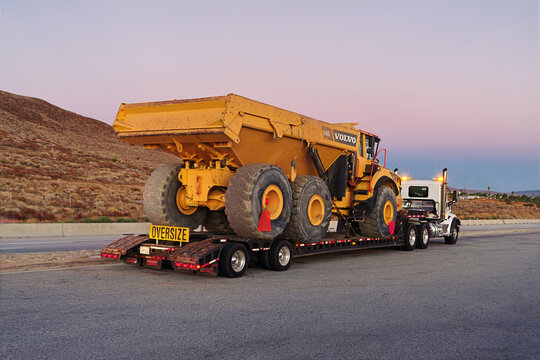 Oversized mining haul truck transported on a semi‑trailer at a rest stop