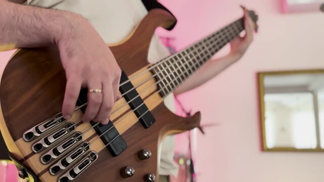 Musician playing natural wood five string bass guitar