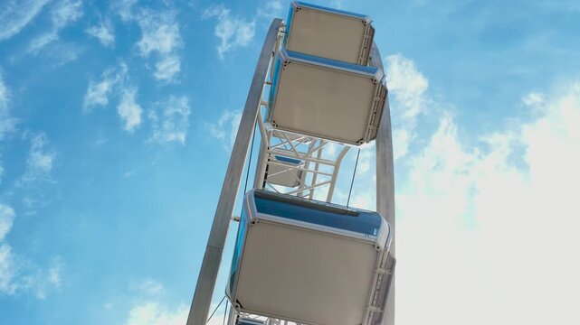 Low angle view of modern ferris wheel cabins against blue sky representing urban tourism infrastructure and smart city leisure industry development