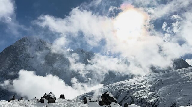 Sun shining through clouds over snowy Himalayan peaks in Nepal