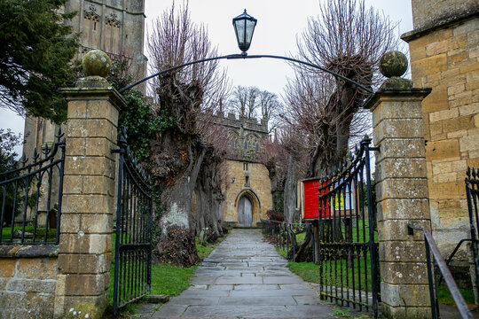 Entrance view of St James' Church in the Cotswolds. This historic &ldquo;wool church&rdquo; is built from honey-coloured Cotswold stone and is approached via a path lined with ancient pollarded lime trees