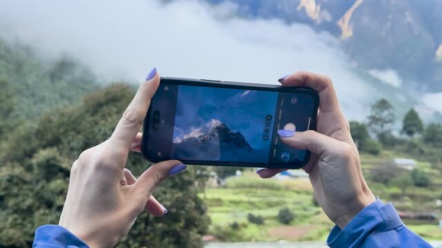 Woman taking smartphone photo of Himalayan mountains in Nepal