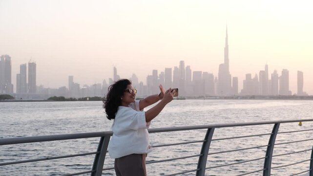 Professional real estate agent filming lifestyle marketing content outdoors beside Dubai waterfront with Burj Khalifa skyline