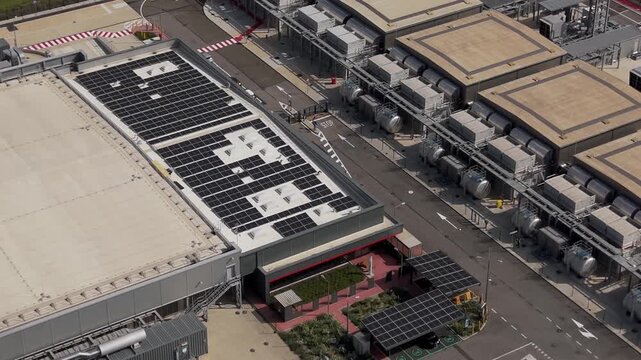 Modern server infrastructure campus filmed from above in Lombardy, Italy showing advanced cloud technology facilities, AI processing systems and digital operations.