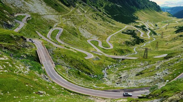 Cinematic camera pan over the winding Transfagarasan highway in the Fagaras Mountains, Romania. Dramatic serpentines, stone bridges and mountain scenery.