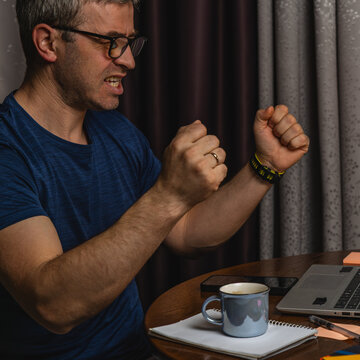 Angry freelancer reacting to problem while working on laptop at night