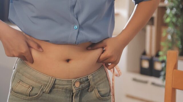 woman's hand holding excessive belly fat, overweight concept