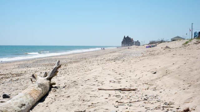Driftwood on a wide sandy Rhode Island beach with historic building