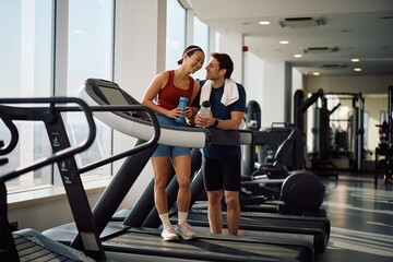 Obraz premium Happy athletic couple having fun during water break in gym.