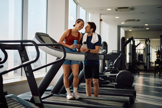 Happy athletic couple having fun during water break in gym.