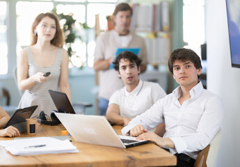 Fototapeta premium Group of employees staff colleagues sit around table, attend presentation demonstration. Working moments, conducting preliminary evaluation of offer.