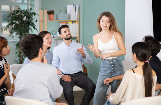 Positive young girl talking to attendees of courses sitting in a circle during classes
