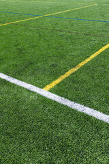 Obraz premium Close-up of an artificial turf sports field with marked lines crossing on synthetic grass. Outdoor sports surface suitable for football, soccer, training, and recreational activities.
