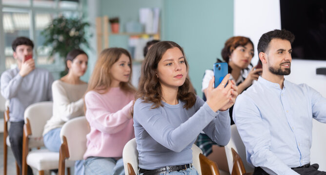 Group of classmates holding up mobile devices to take photos during a training session
