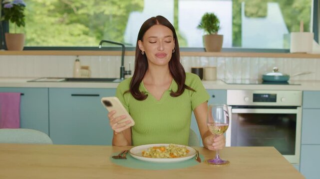 Happy young woman laughing while texting on smartphone and drinking wine, 4K slow motion