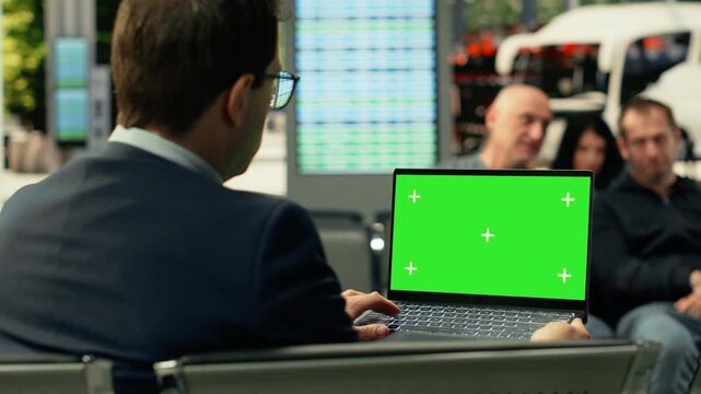 Isolated green screen laptop with seated commuter in modern bus terminal during rush hour. Busy passengers and groups move through urban transit hub, dynamic city travel atmosphere.