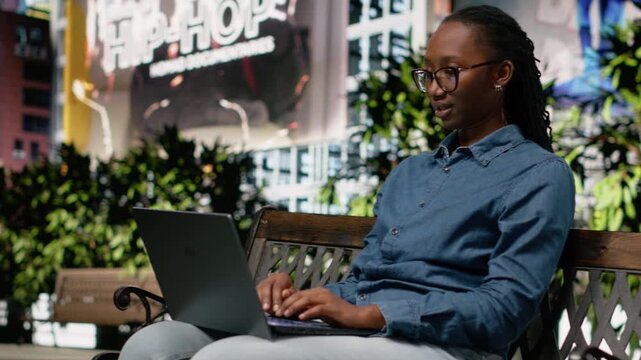 African american woman closing laptop and leaving the park after working, finishing tasks and workday and getting up. Turn off portable computer, metropolitan city life space downtown.