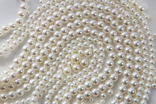 Beautiful necklace and single pearls on white satin background for background or wedding jewellery with copy space