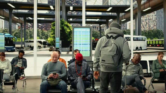 Multiethnic group of travelers talking about route waiting in bus station, becoming friends while waiting for daily commute coach. Passengers chatting and laughing at metropolitan terminal.