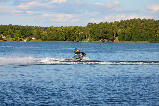 Man riding a jet ski making a turn on a scenic summer lake. Active water sports